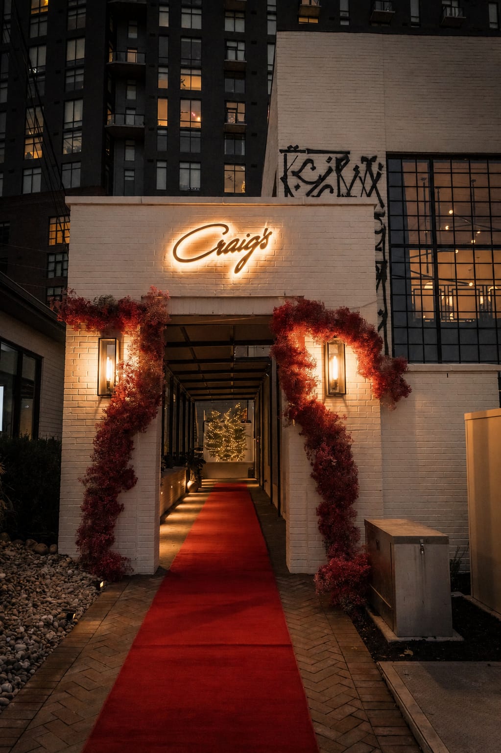 The Craig's neon sign above the red-carpet entrance walkway, framed by red florals